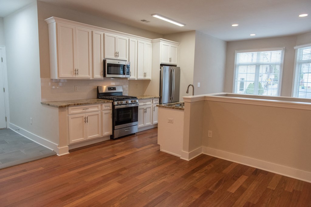 a kitchen with white cabinets and a wooden floor