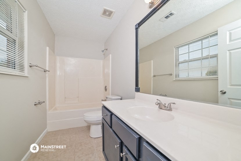 the bathroom has a large mirror and a white sink and toilet