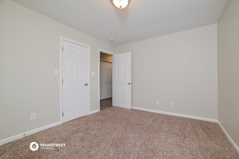 the spacious living room of a manufactured home with white doors and carpet