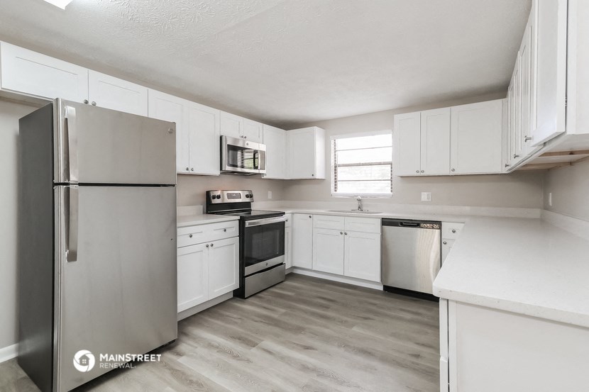a white kitchen with white cabinets and stainless steel appliances