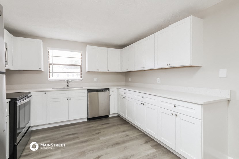 a white kitchen with white cabinets and a window