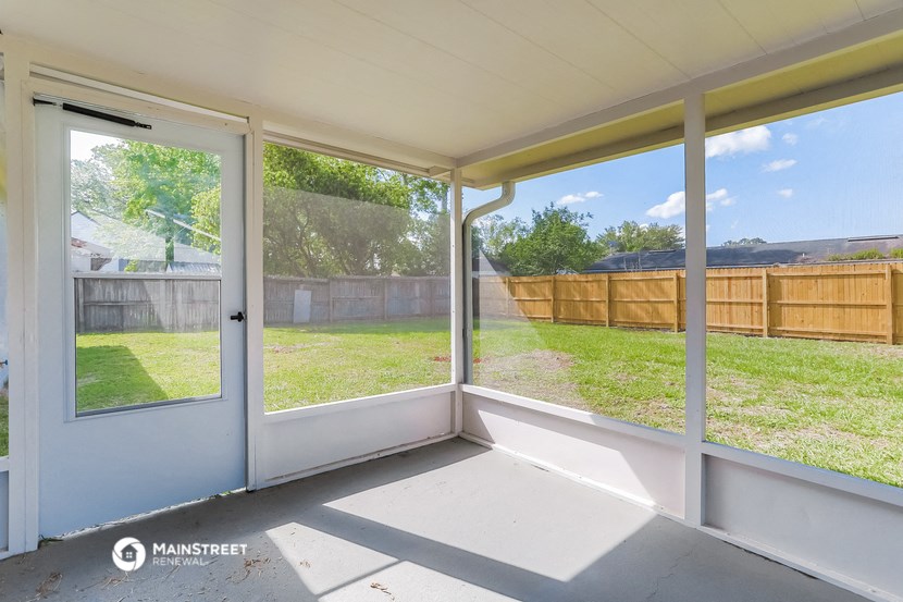 a screened in porch with glass doors and a backyard