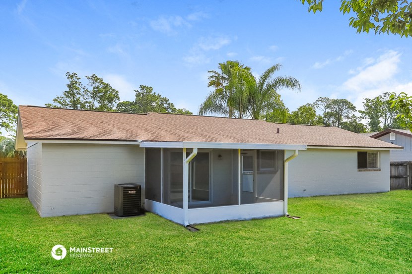 a small white house with a lawn and a palm tree