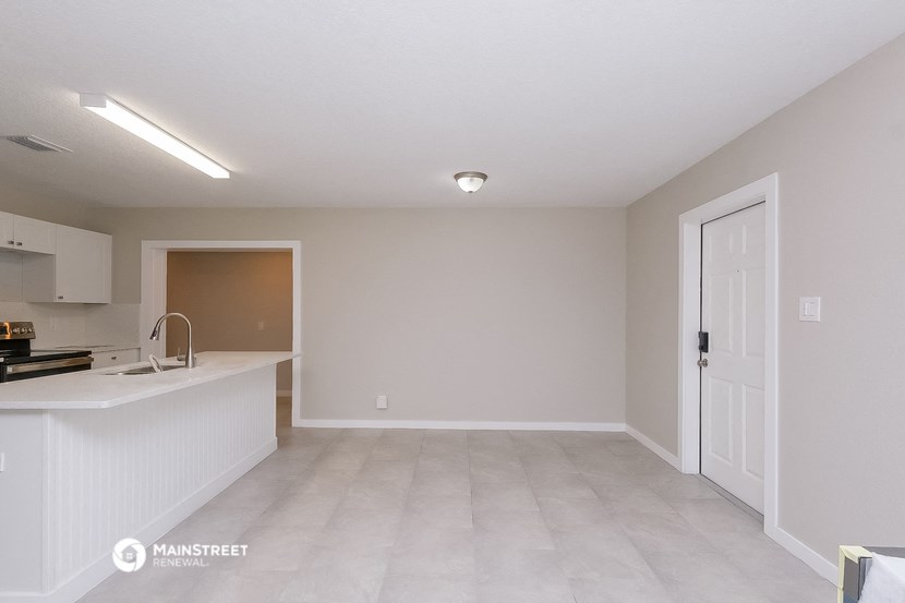 an empty kitchen and living room with a door to the bathroom