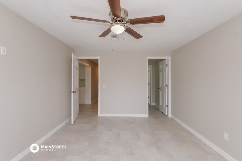 a living room with a ceiling fan and a door to a hallway