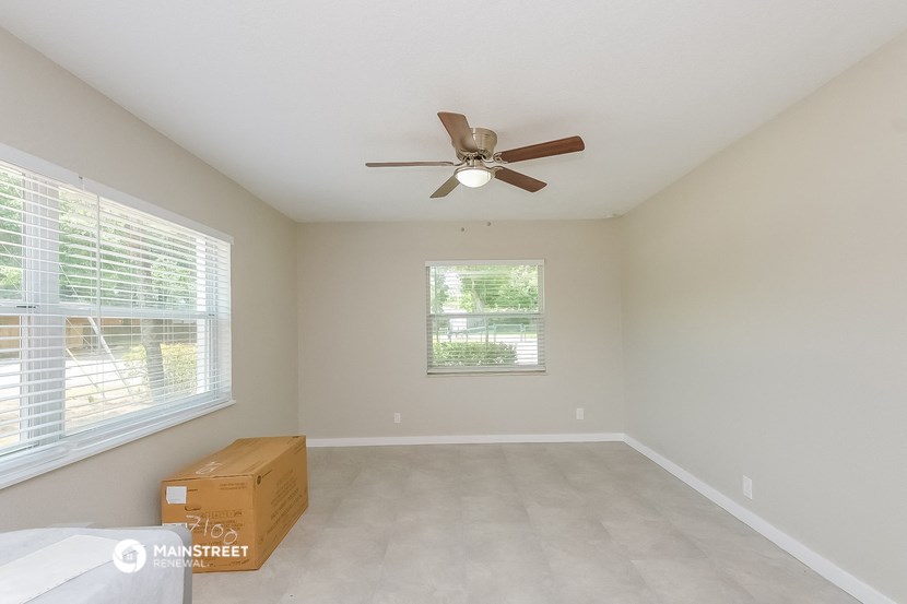 the master bedroom has a large window and a ceiling fan