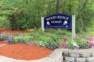 a sign for wood ridge homes in front of flowers
