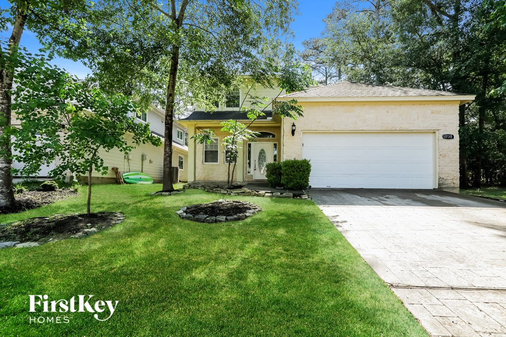 A house with a garage is surrounded by trees and has a well-maintained lawn.