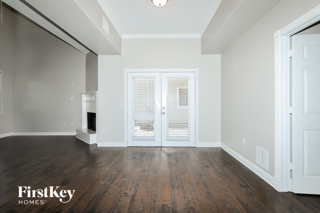 A spacious room with wooden floors and a white door.