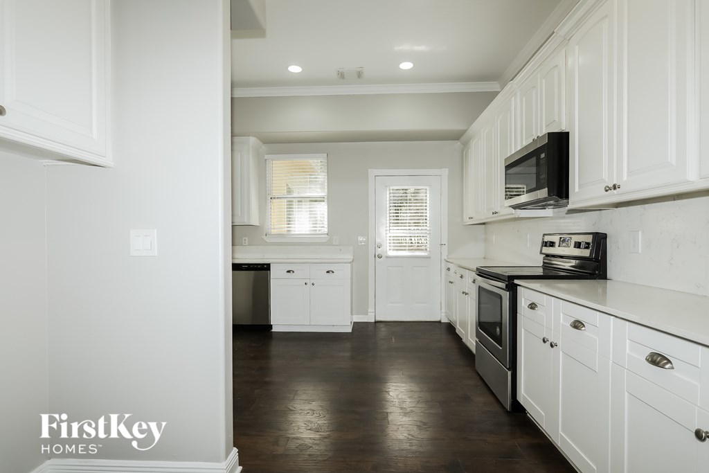 A kitchen with white cabinets and a black microwave.