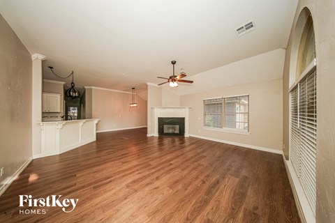 A spacious living room with wood flooring and a fireplace.