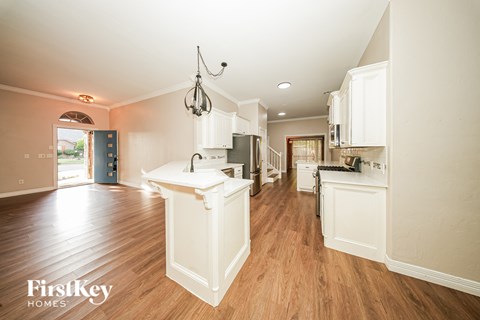 A kitchen with wooden floors and white cabinets.