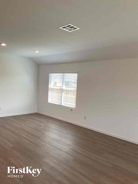 an empty living room with wood floors and a window