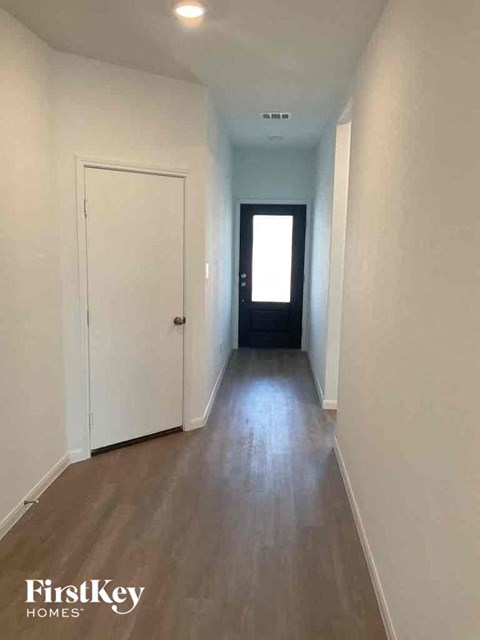 a hallway with white walls and a white door and wooden floors