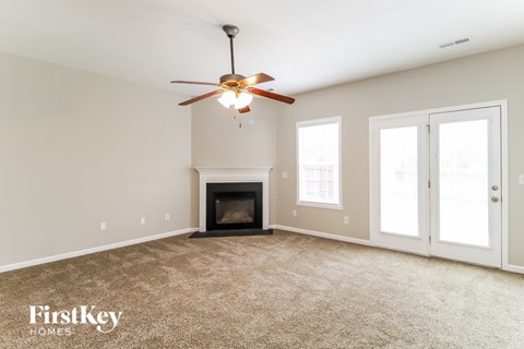 A spacious room with a fireplace and a ceiling fan.