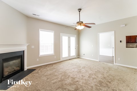 A spacious room with a fireplace and a ceiling fan.