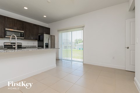 A kitchen with a white counter top and a window with blinds.