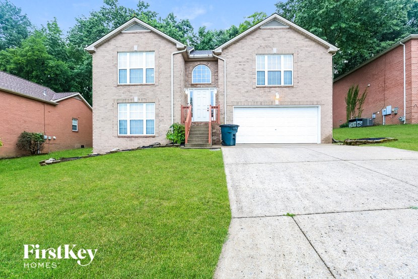 a beige brick house with a white garage door and a lawn