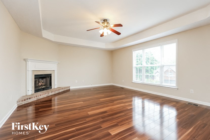 an empty living room with a fireplace and a ceiling fan