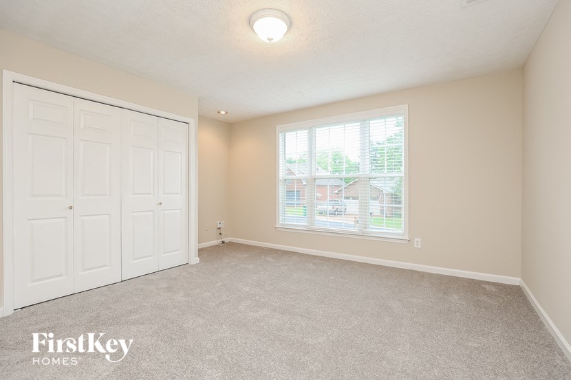 an empty bedroom with a large window and a closet