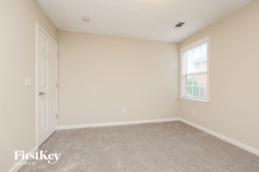 the bedroom of a home with a white door and carpet