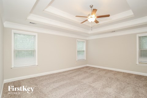 the living room of a new home with a ceiling fan and carpet