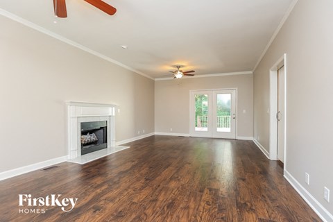 an empty living room with a fireplace and a ceiling fan