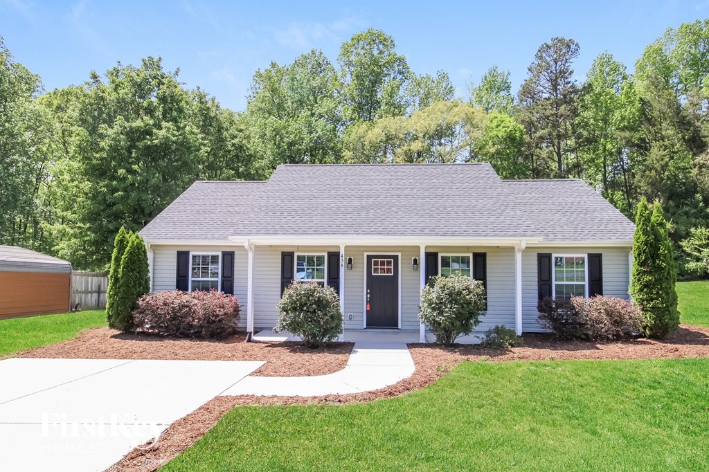 A white house with a grey roof and a brown garage door.
