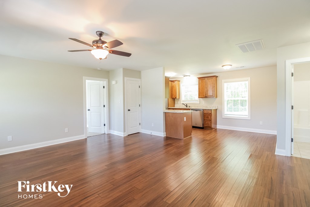 A spacious room with wooden floors and a ceiling fan.