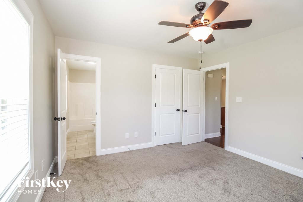 A room with a ceiling fan and carpeted floor.