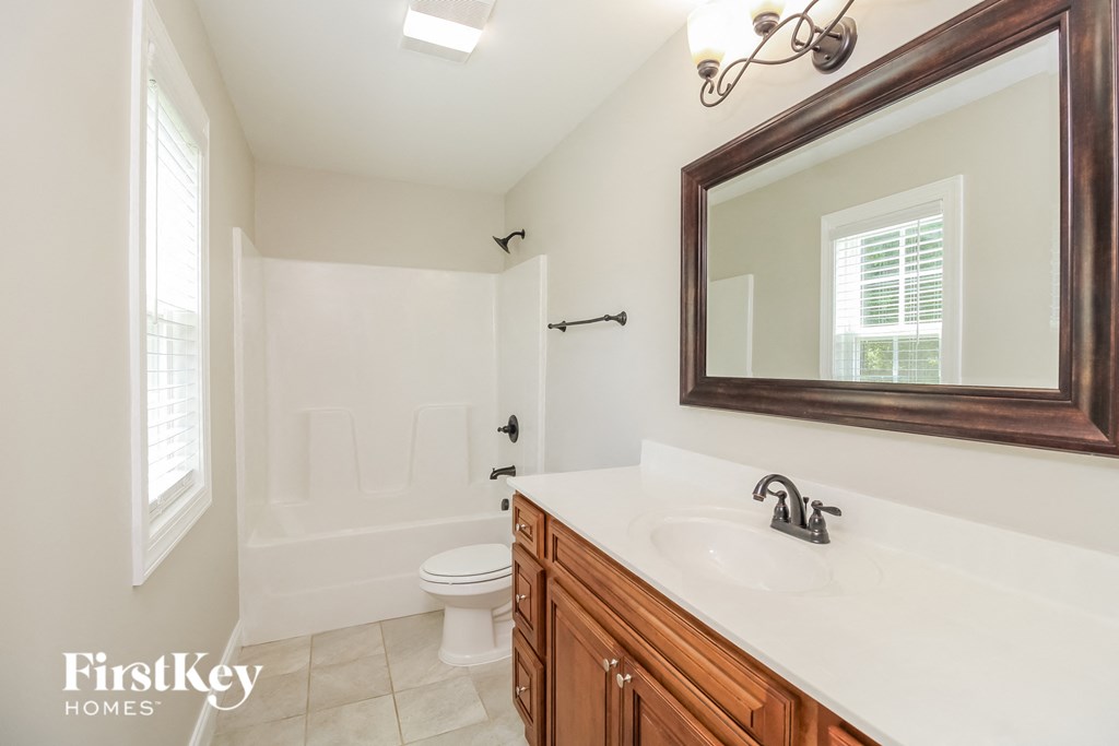A bathroom with a toilet, sink and mirror.