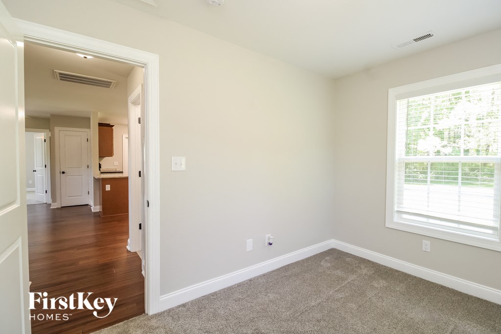 A room with a carpeted floor and a window with blinds.