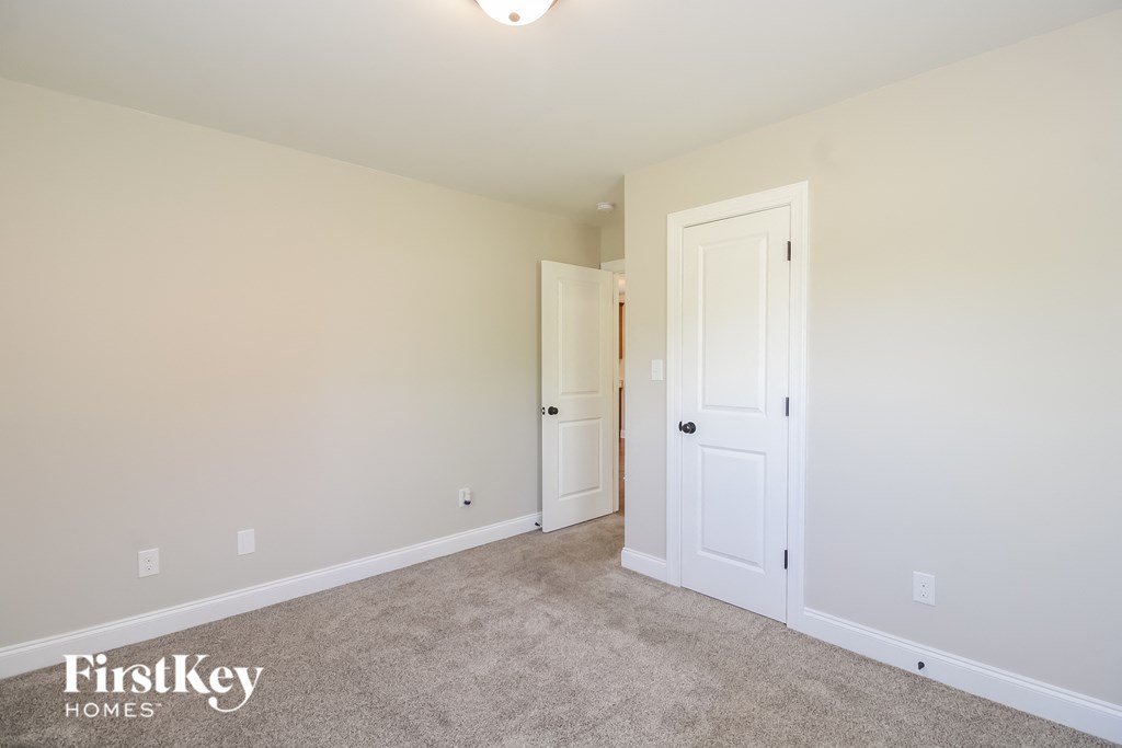 A room with a carpet floor and two doors.
