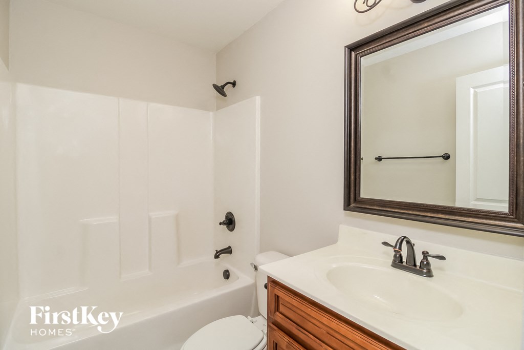 A white bathroom with a white tub and a white toilet.