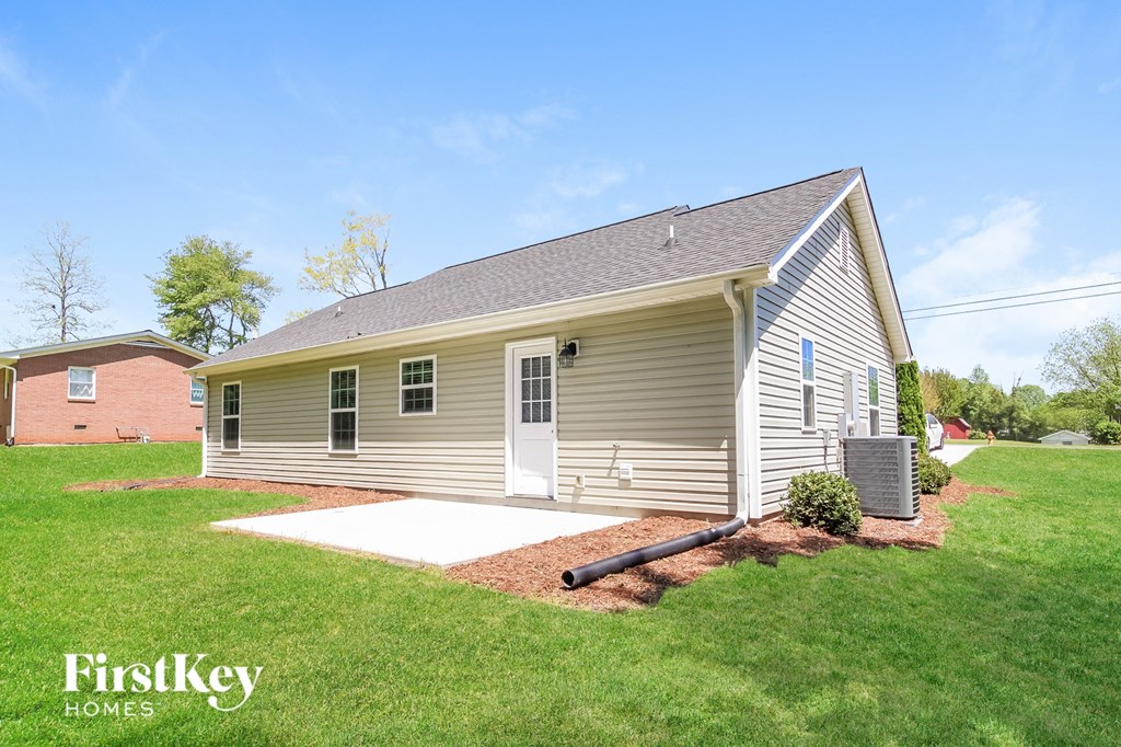 A house with a grey siding and a brown roof is for sale.