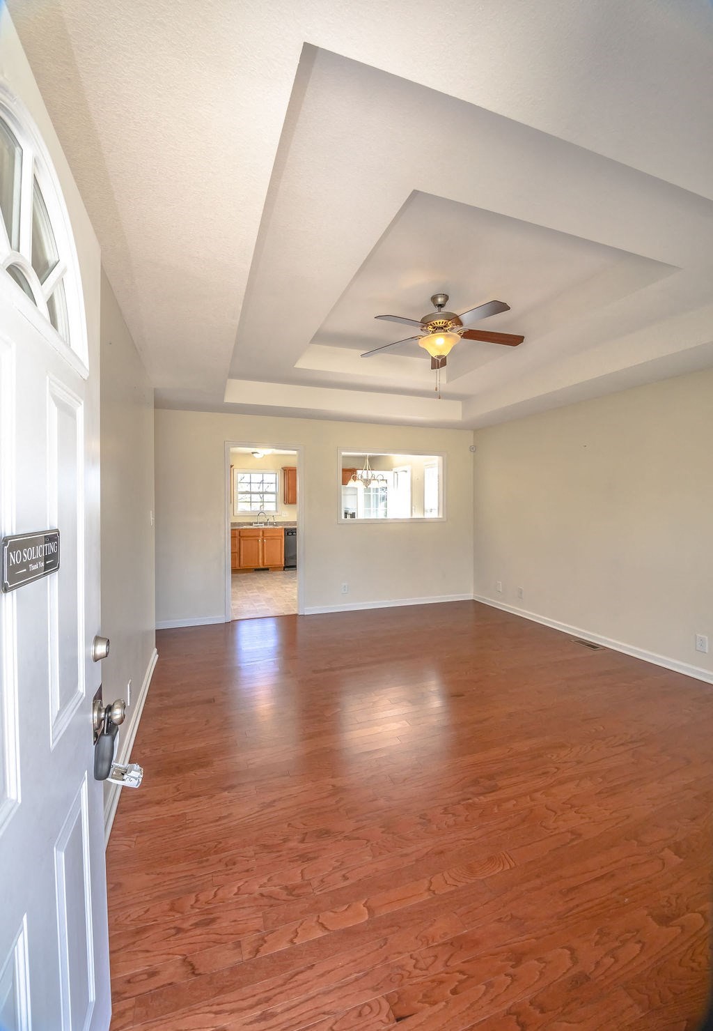 an empty living room with wood floors and a ceiling fan