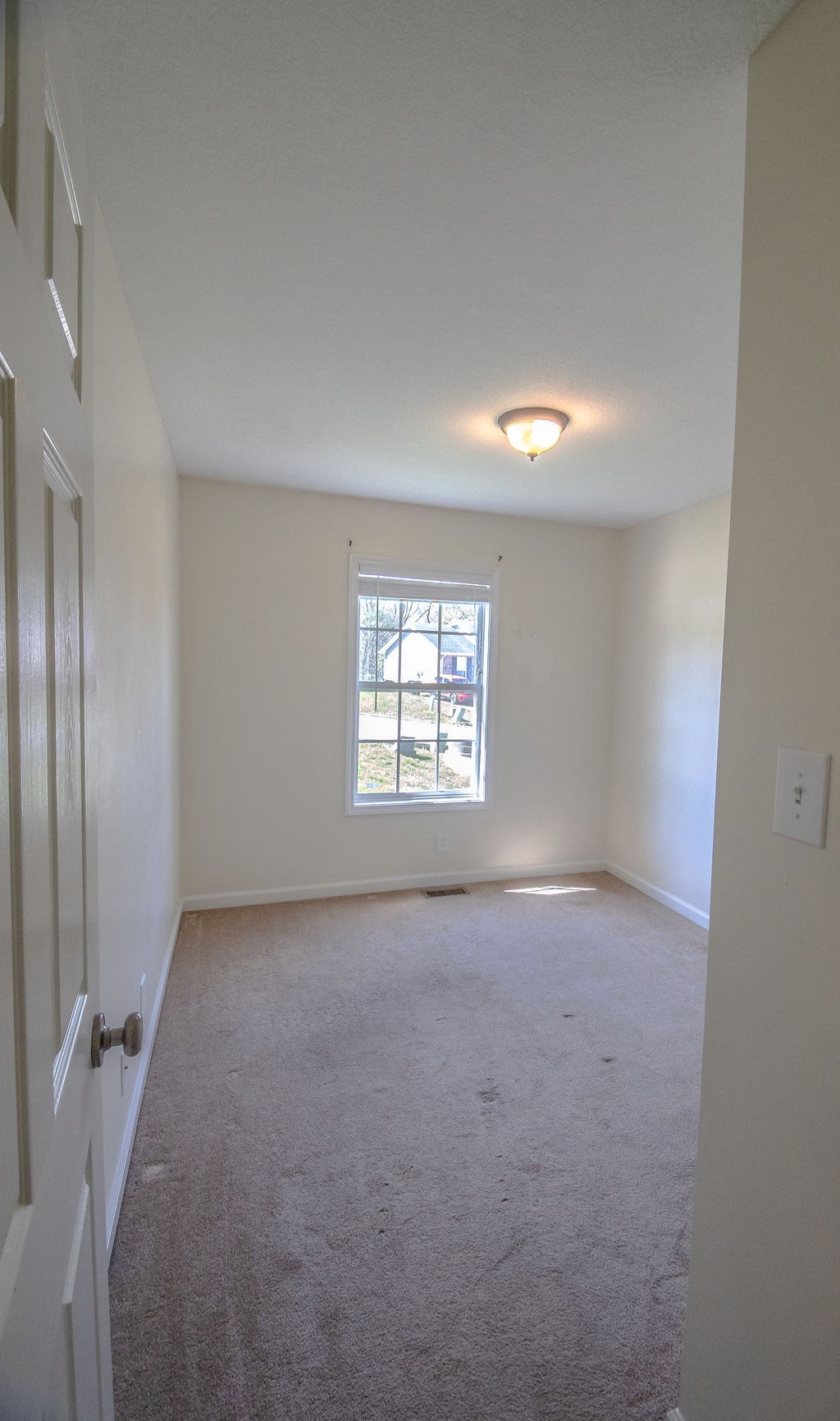 a bedroom with a carpeted floor and a window