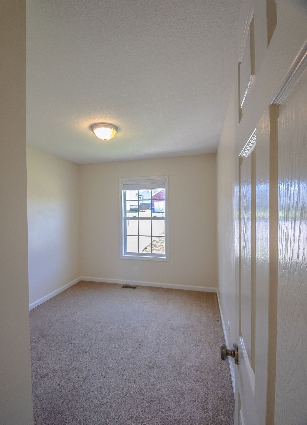 an empty bedroom with a window and a door