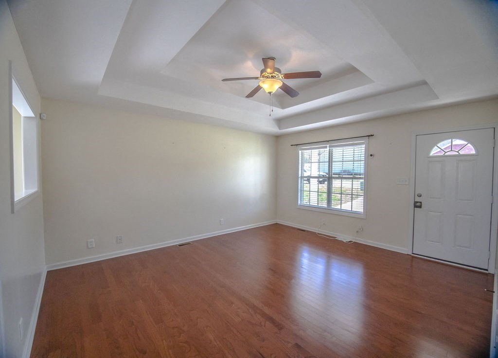 an empty living room with a ceiling fan and a door
