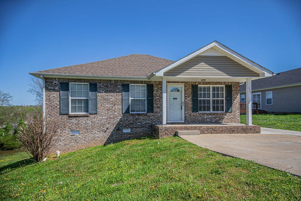 a small brick house with a porch and a driveway