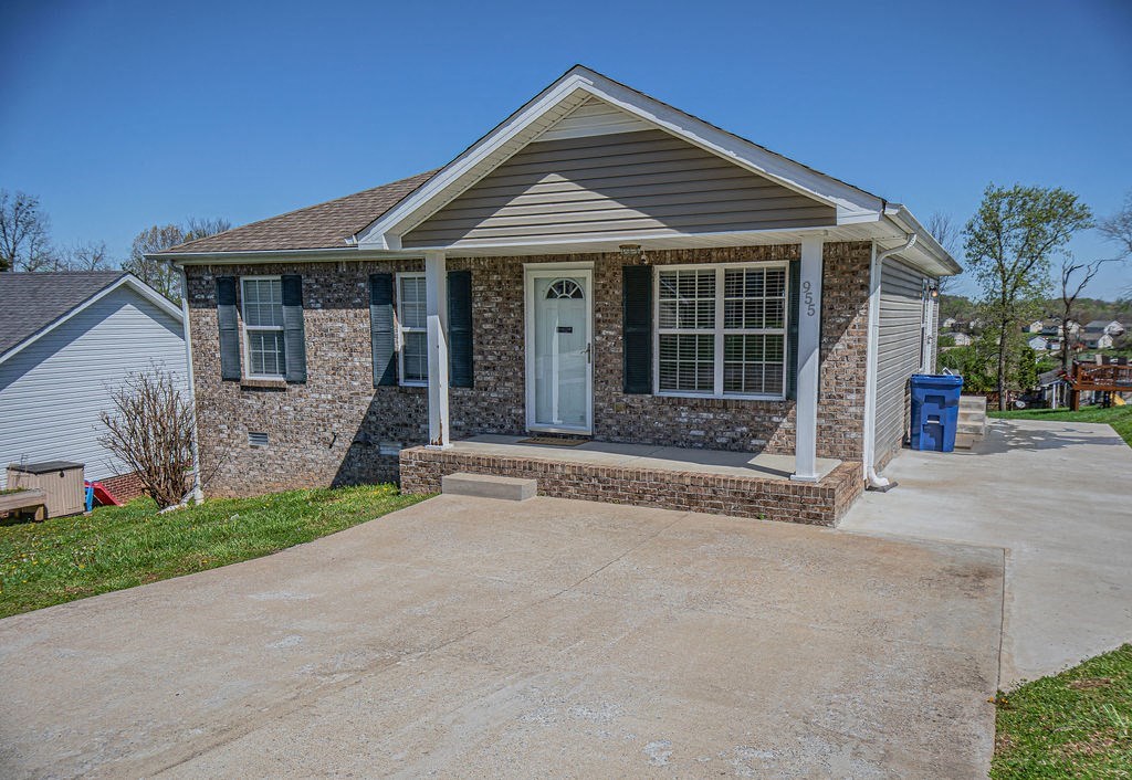 a small brick house with a driveway and a white door