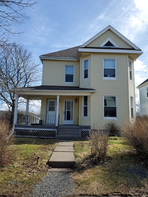 A yellow house with a porch and a small front yard.