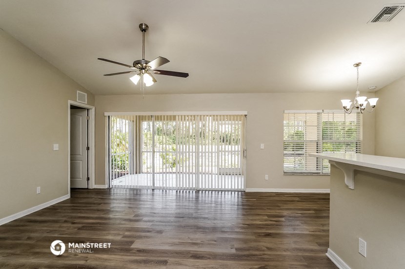 an empty living room with a ceiling fan and a window