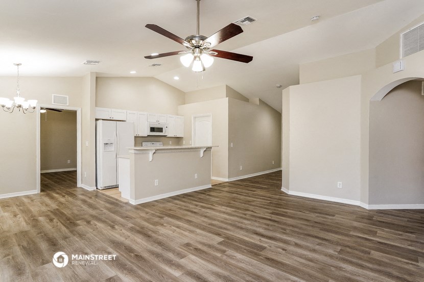 a living room with a kitchen and a ceiling fan