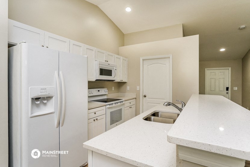 a kitchen with white cabinets and appliances and a sink