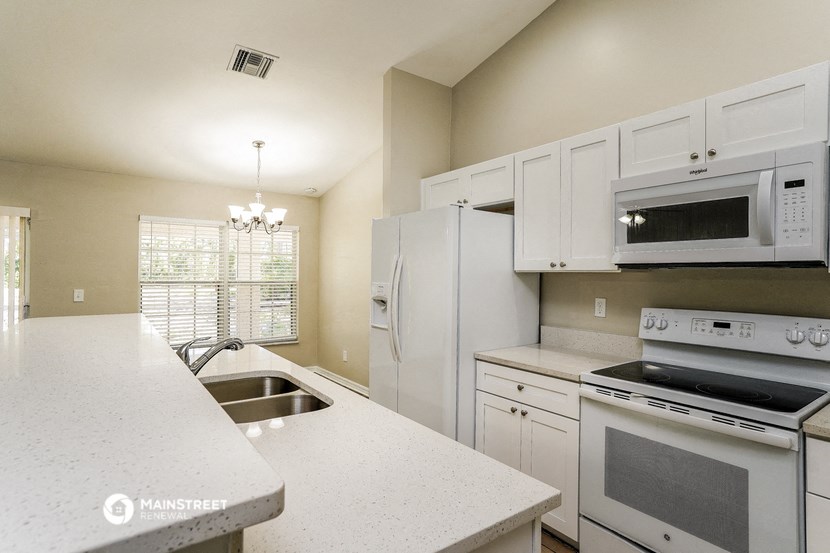 a kitchen with white cabinets and appliances and white counter tops