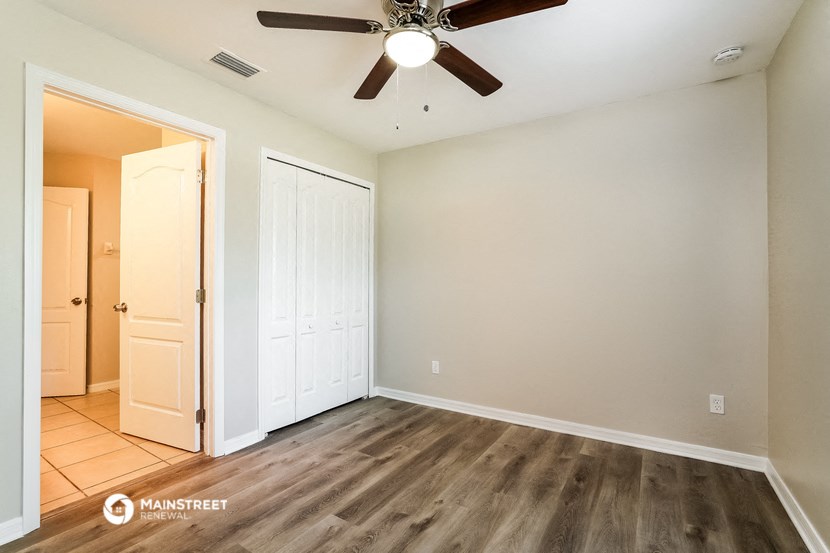 an empty living room with wood floors and a ceiling fan