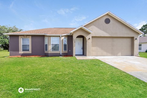 a beige house with a garage door and a lawn