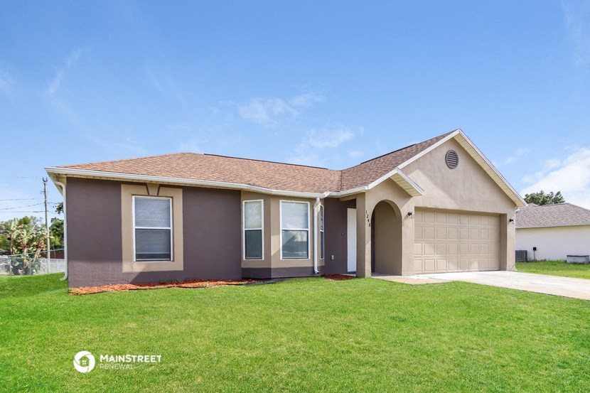 a beige house with a lawn and a garage