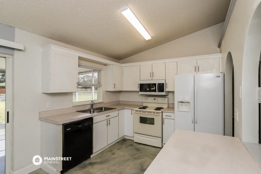 a kitchen with white cabinets and a sink and a refrigerator